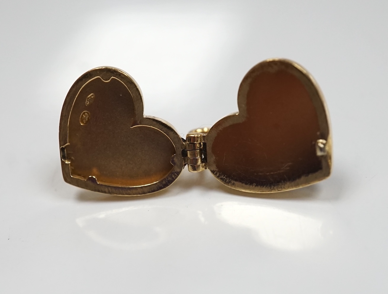 A modern Louis Vuitton 750 yellow metal and garnet? set heart shaped locket, width 15mm, gross weight 5.9 grams. Condition - poor to fair